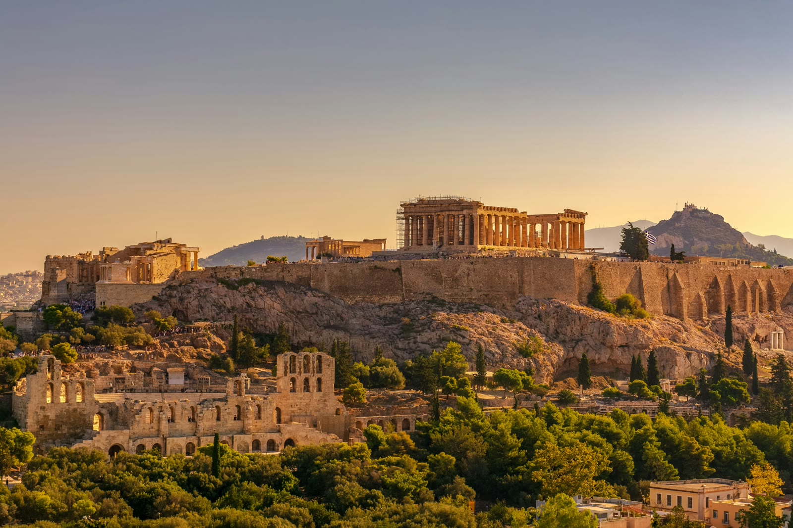 Acropolis of Athens illuminated during golden hour with city skyline below, Attica, Greece