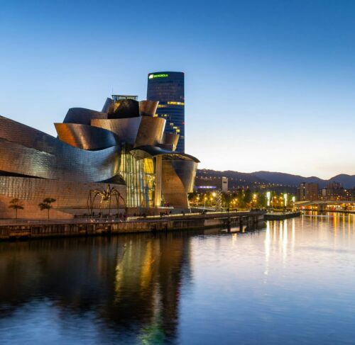 Guggenheim Museum Bilbao alongside the Nervion River with modern architecture and city skyline, Basque Country Spain