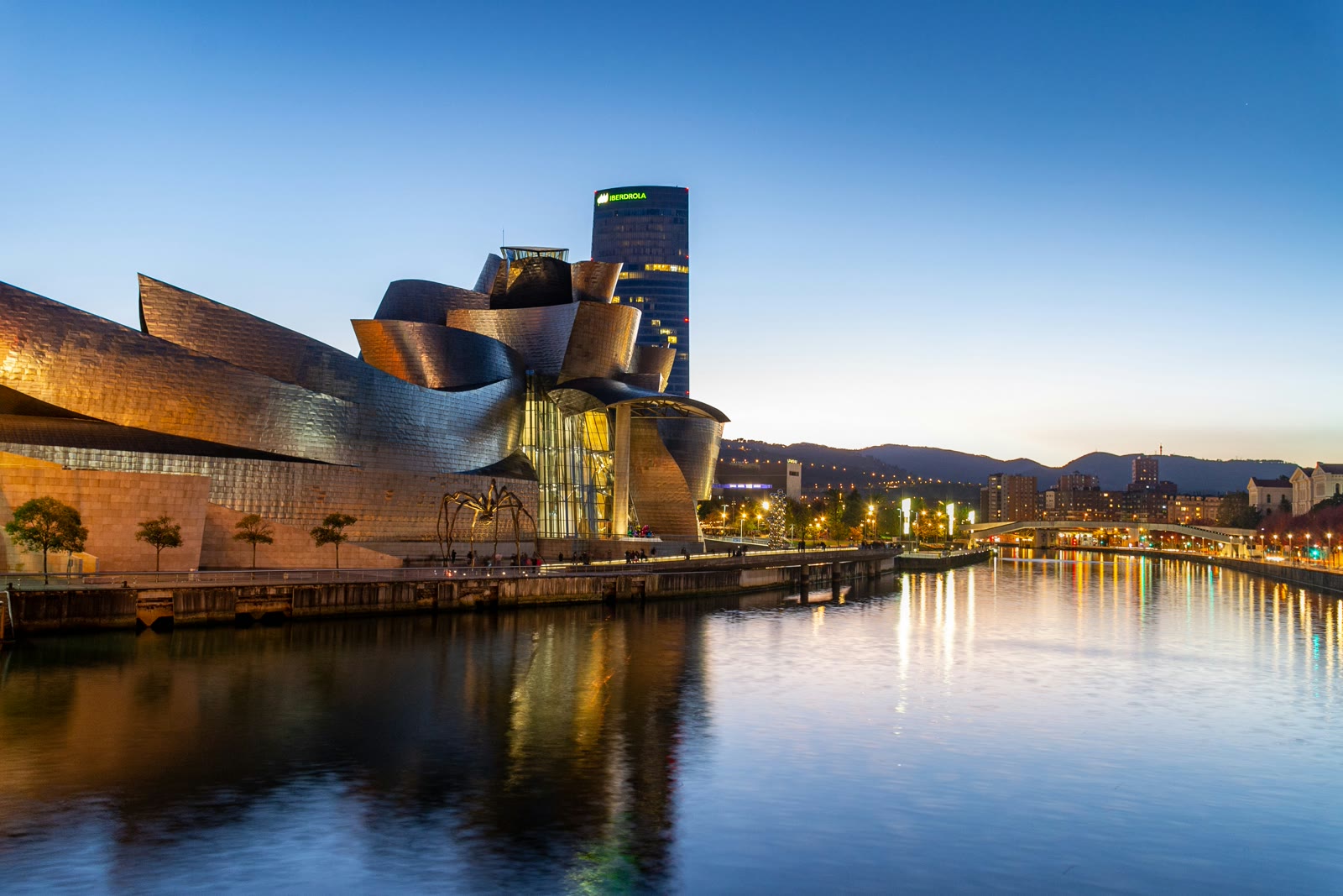 Guggenheim Museum Bilbao alongside the Nervion River with modern architecture and city skyline, Basque Country Spain