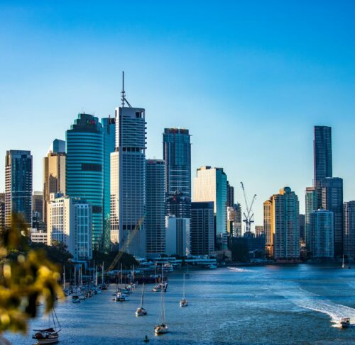 Brisbane city skyline along the Brisbane River under bright blue sky during daytime