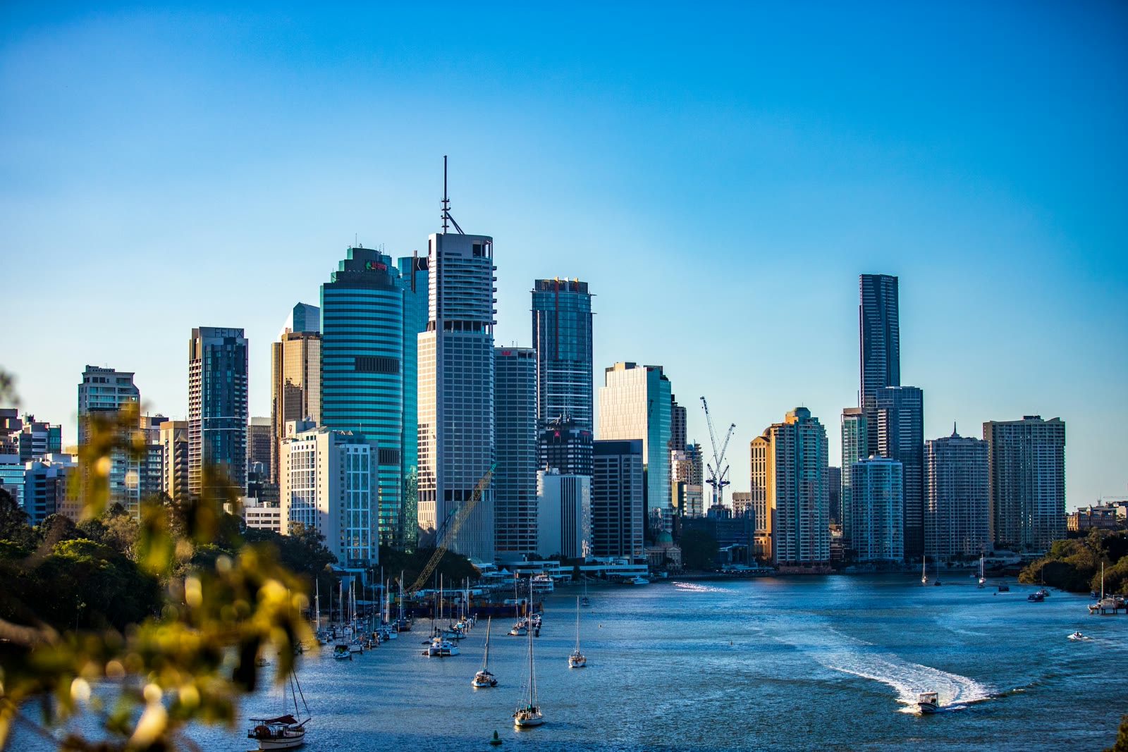 Brisbane city skyline along the Brisbane River under bright blue sky during daytime