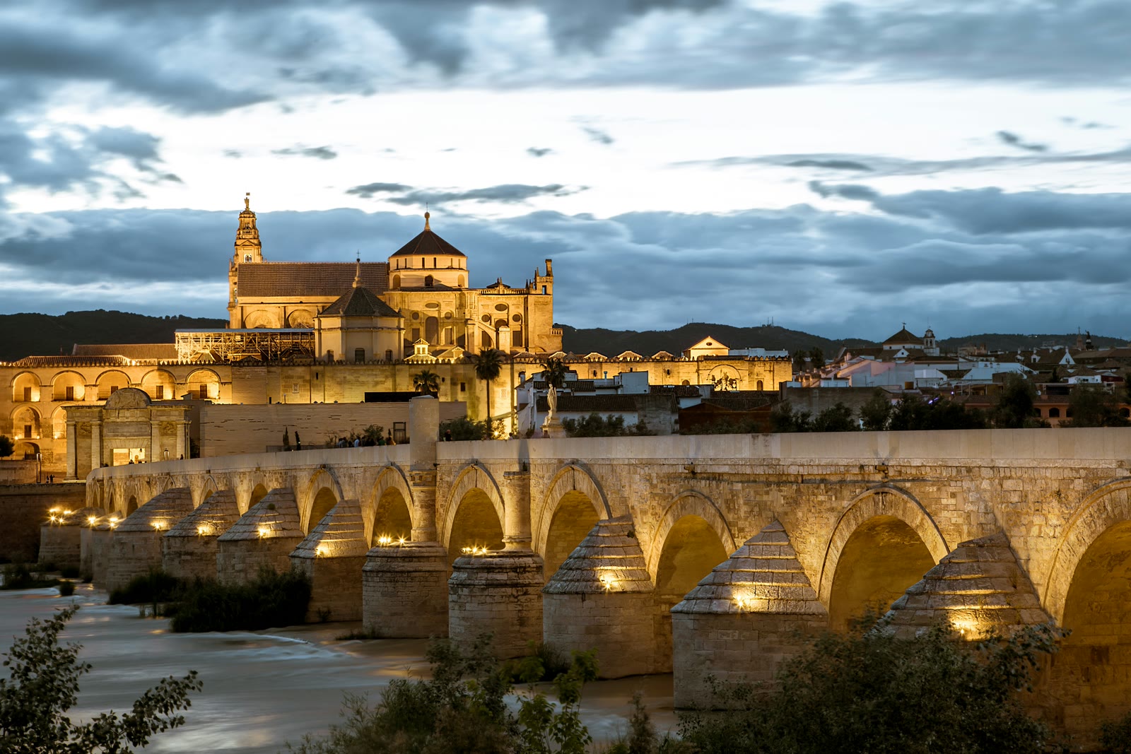 Illuminated Mosque-Cathedral of Córdoba and Roman Bridge over the Guadalquivir River at dusk, Andalusia, Spain