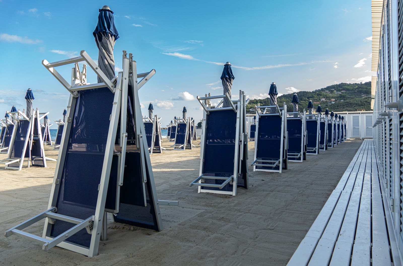 Row of blue beach chairs on the sandy shore of Diano Marina, Liguria