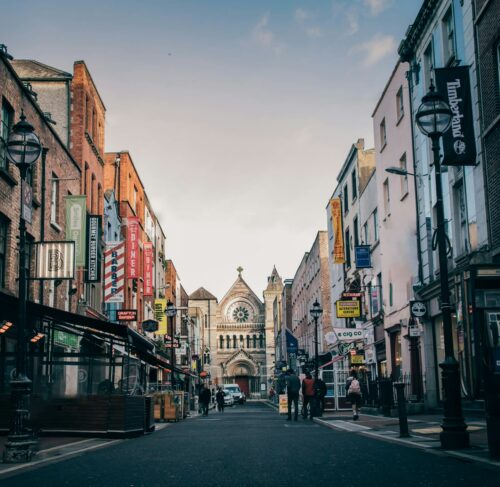 People walking on Dublin street toward church spire, Ireland cityscape