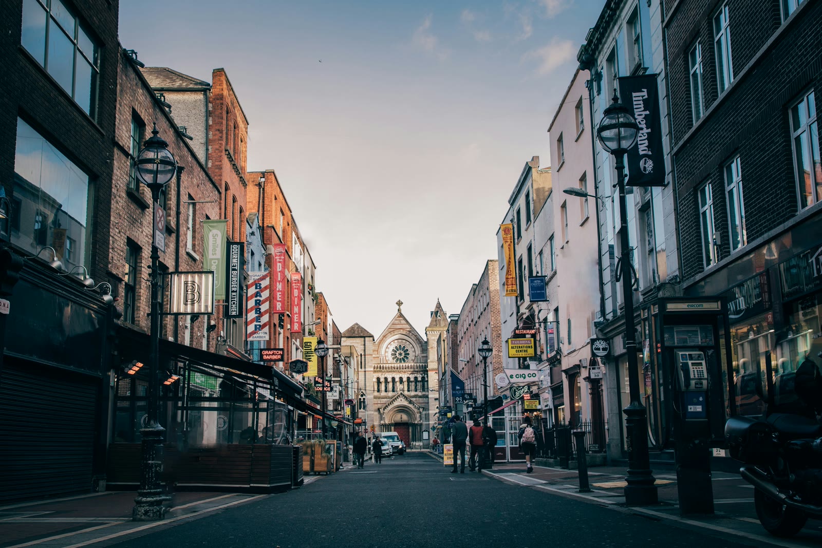 People walking on Dublin street toward church spire, Ireland cityscape