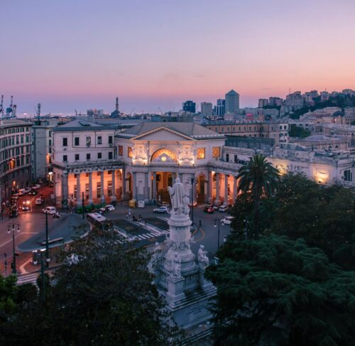 Panoramic sunset view over Genoa Italy old town with colorful buildings, port and Mediterranean Sea in the distance