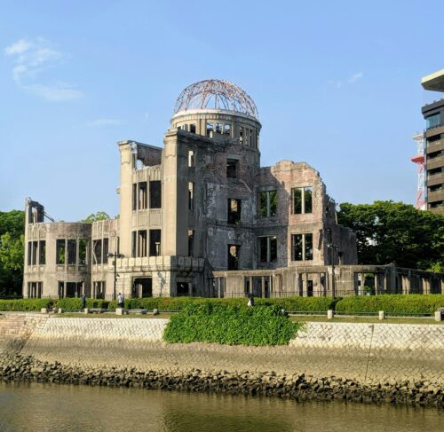 Hiroshima Atomic Bomb Dome memorial building by the Motoyasu River with modern city skyline behind