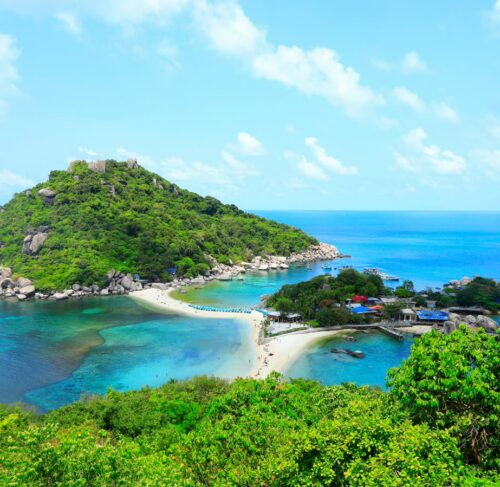 Tropical island scene on Koh Samui with green palm trees, blue sky, and crystal-clear water