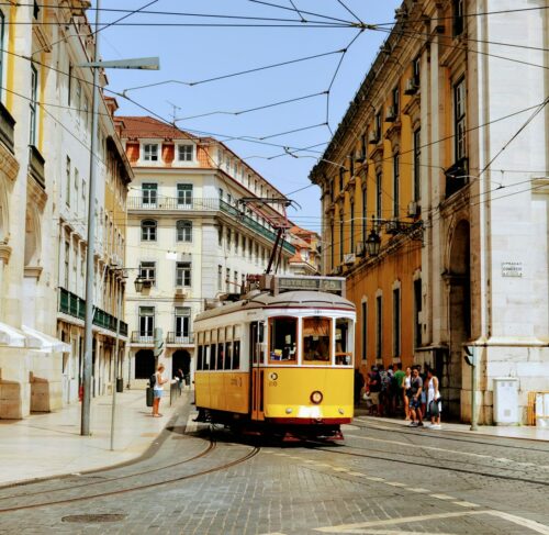Yellow Tram 28 on a Lisbon street with traditional Portuguese buildings and sunny sky
