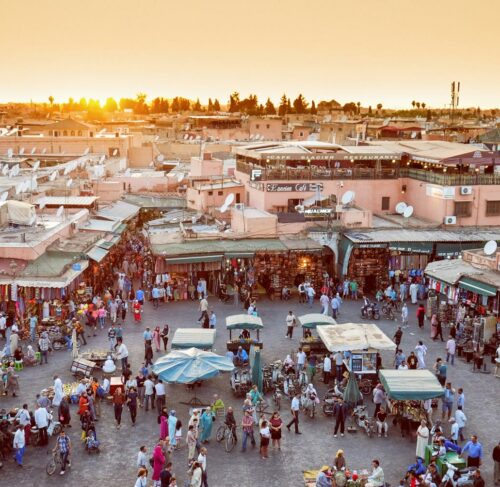 People walking through a narrow alley in the Marrakech medina souq with traditional market stalls