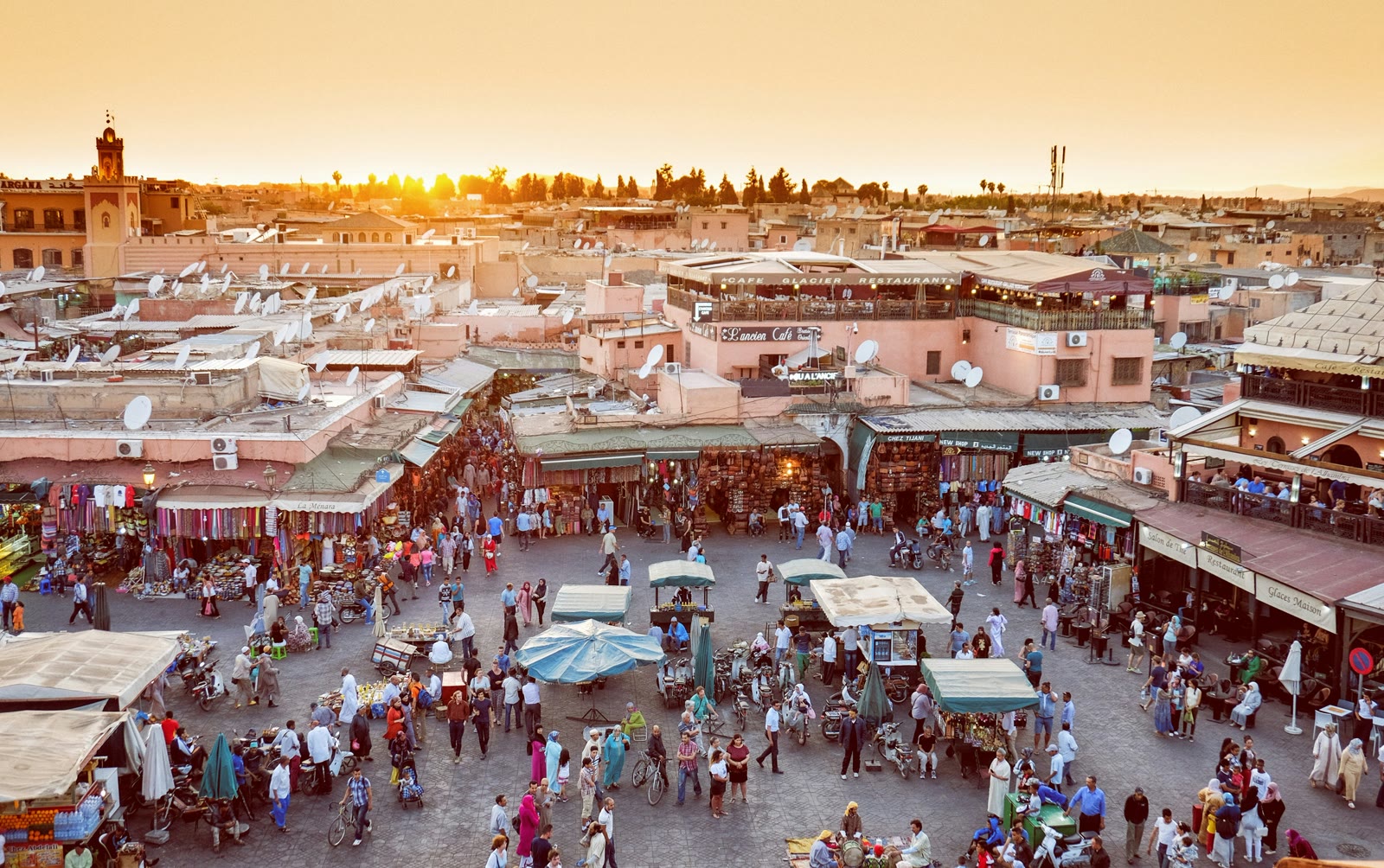 People walking through a narrow alley in the Marrakech medina souq with traditional market stalls