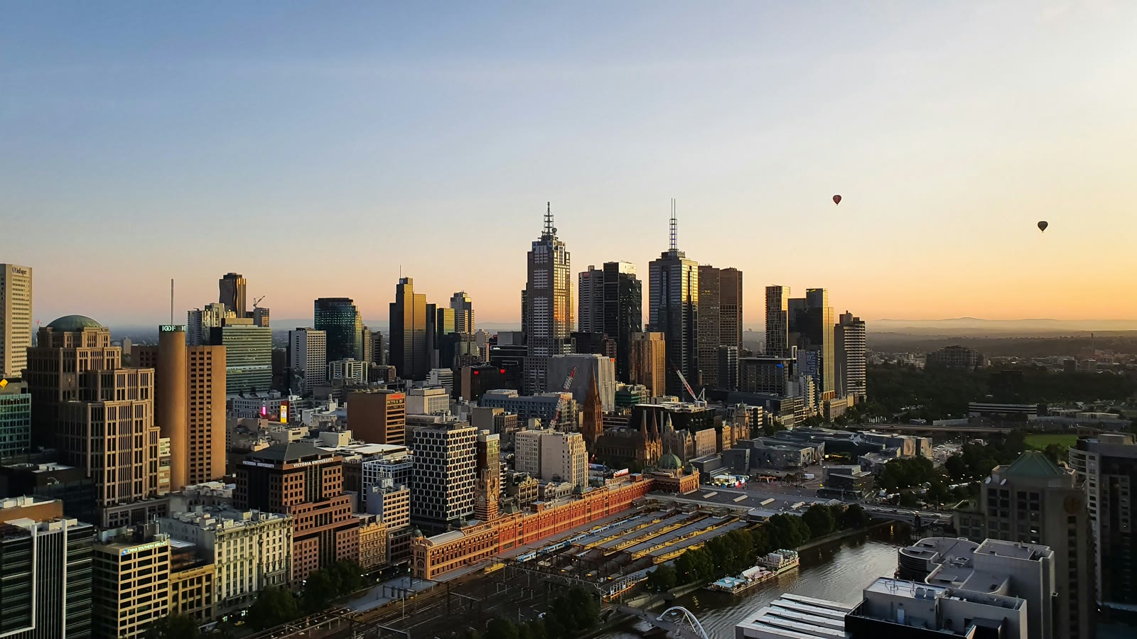 Daytime panoramic view of Melbourne's city skyline with modern skyscrapers and the Yarra River visible