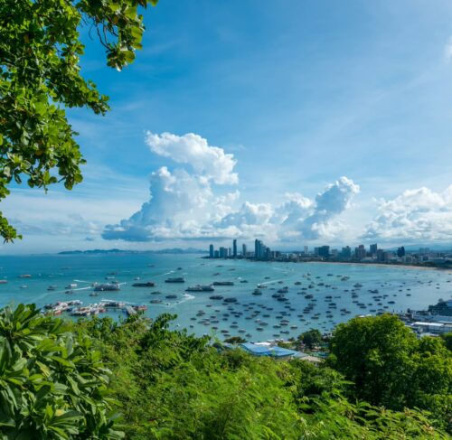 Panoramic view of Pattaya Bay with city skyline, coastline, and calm blue water under partly cloudy sky