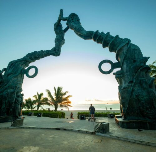 Playa del Carmen Quinta Avenida with iconic standing statue and palm trees under blue sky