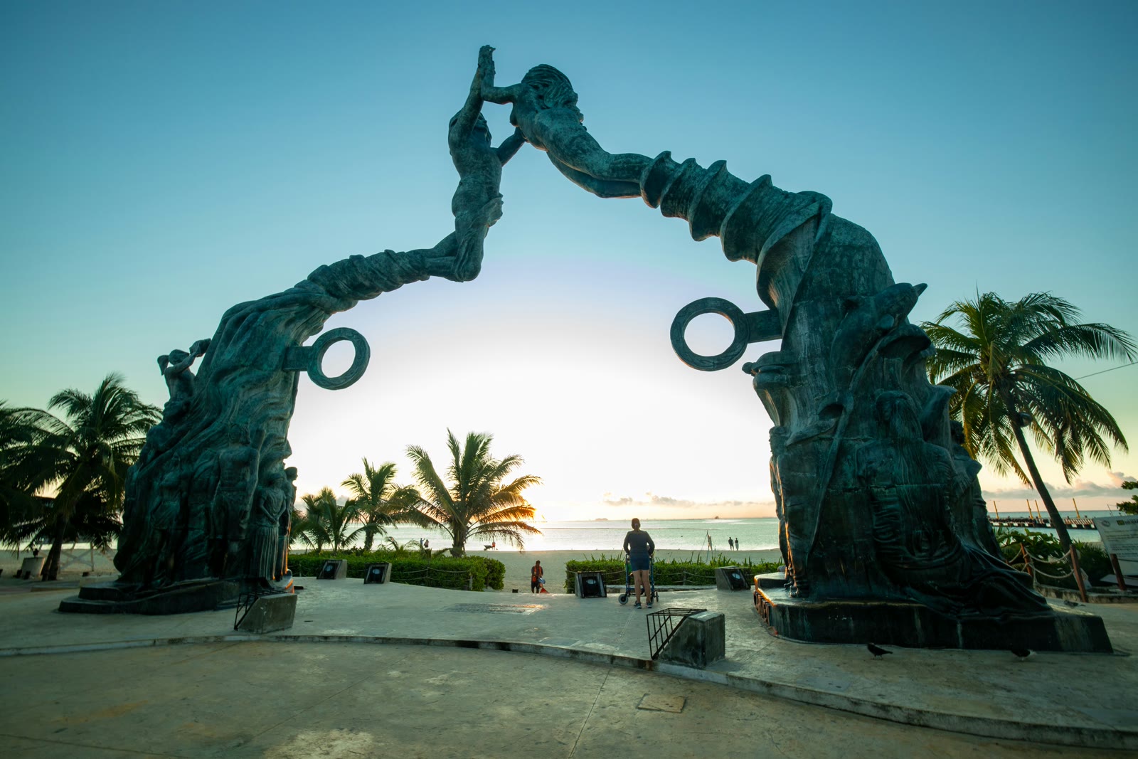 Playa del Carmen Quinta Avenida with iconic standing statue and palm trees under blue sky