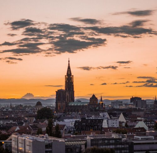 Strasbourg Petite France district at sunset with River Ill and half-timbered buildings under orange sky