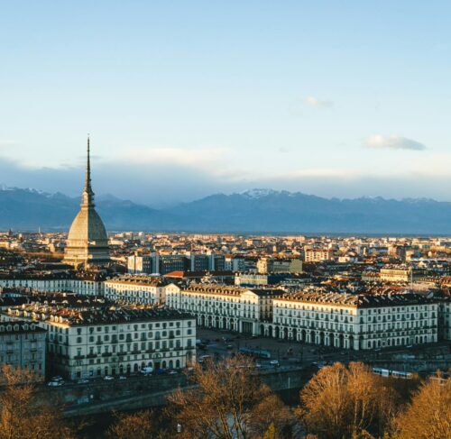 Aerial view of Turin city buildings and streets during the day with Alps mountains in the distance