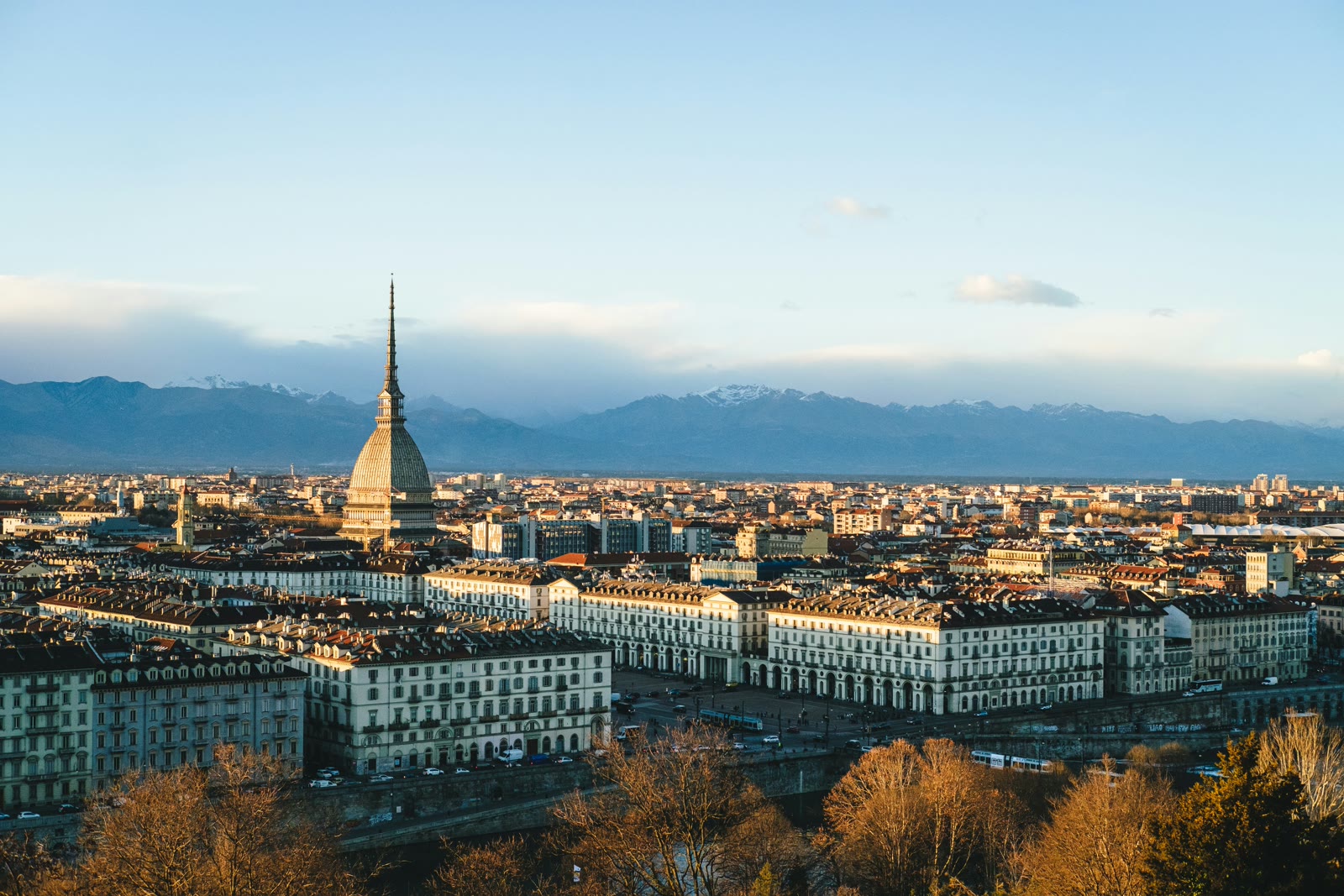 Aerial view of Turin city buildings and streets during the day with Alps mountains in the distance