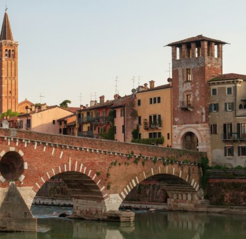 Ponte Pietra bridge over Adige River with Verona old town buildings and hillside in background