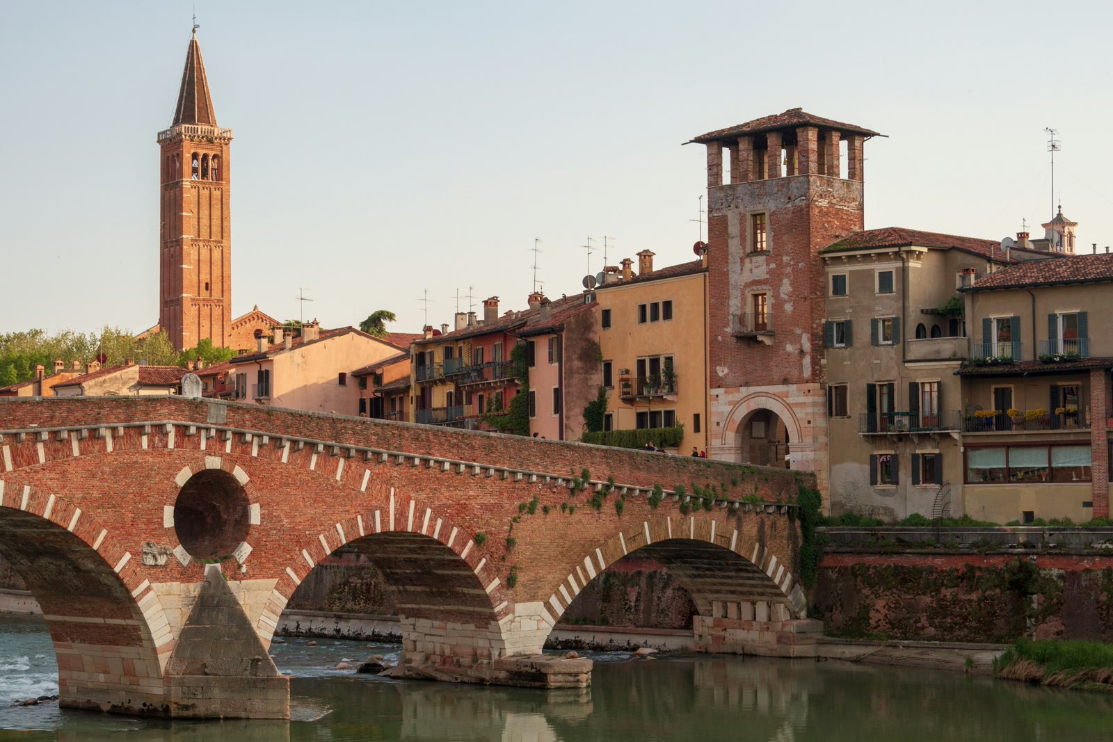 Ponte Pietra bridge over Adige River with Verona old town buildings and hillside in background