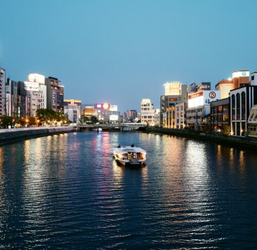 White boat on the river near city buildings in Fukuoka, Japan