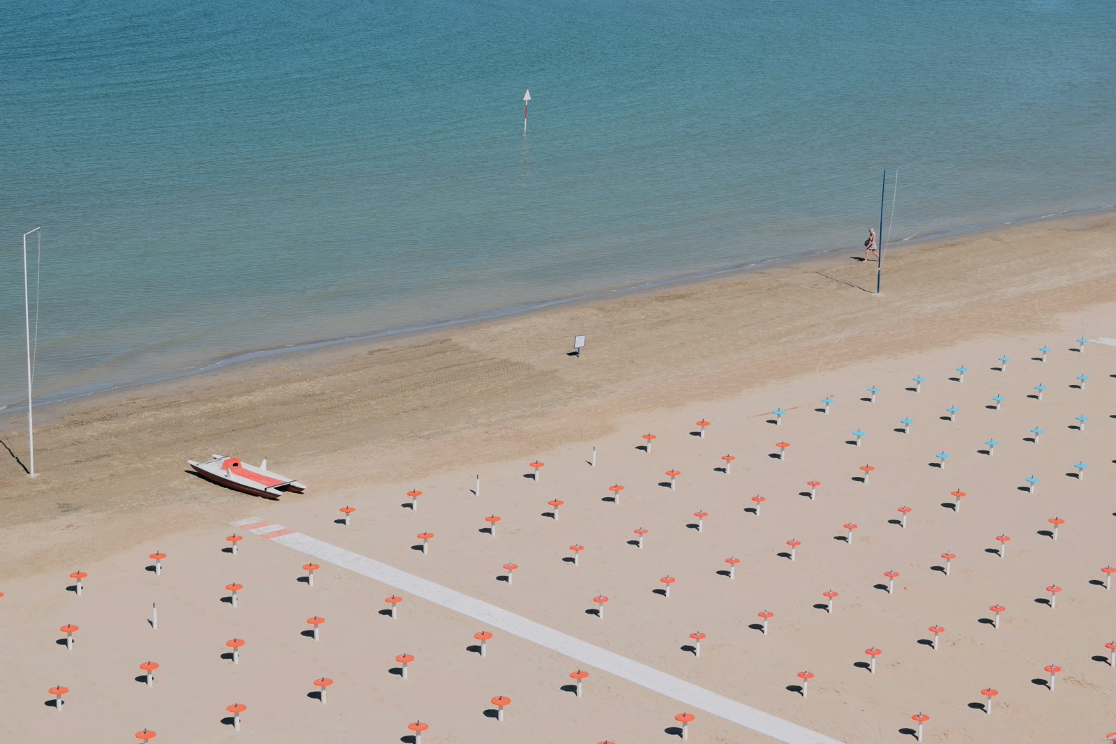 Person walking past fishing boats on the sandy beach in Rimini, Emilia-Romagna, Italy, Adriatic coast