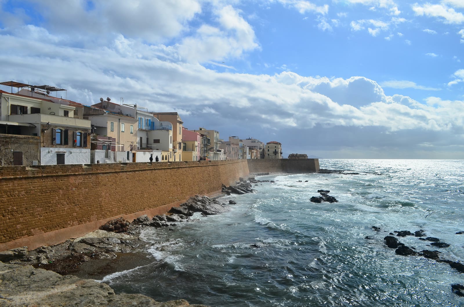 Brown concrete building by the sea under blue sky, Alghero, Sardinia, Italy