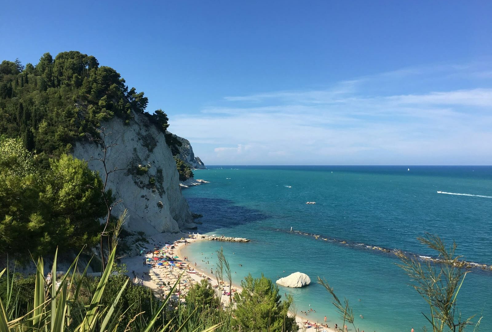 Green and brown rocky mountain alongside blue sea under blue sky, Ancona, Marche, Italy