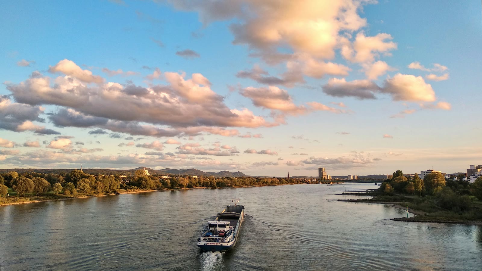 Boat traveling on a river under cloudy sky in Bonn, North Rhine-Westphalia, Germany