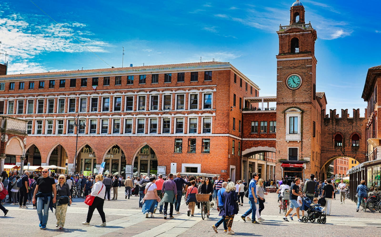 Crowd of people walking around a brick building in Ferrara, Emilia-Romagna, Italy