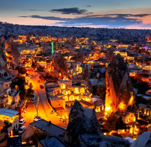 Illuminated town with mountains in background at night in Goreme, Cappadocia, Turkey