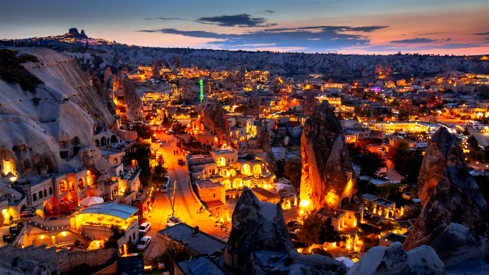 Illuminated town with mountains in background at night in Goreme, Cappadocia, Turkey