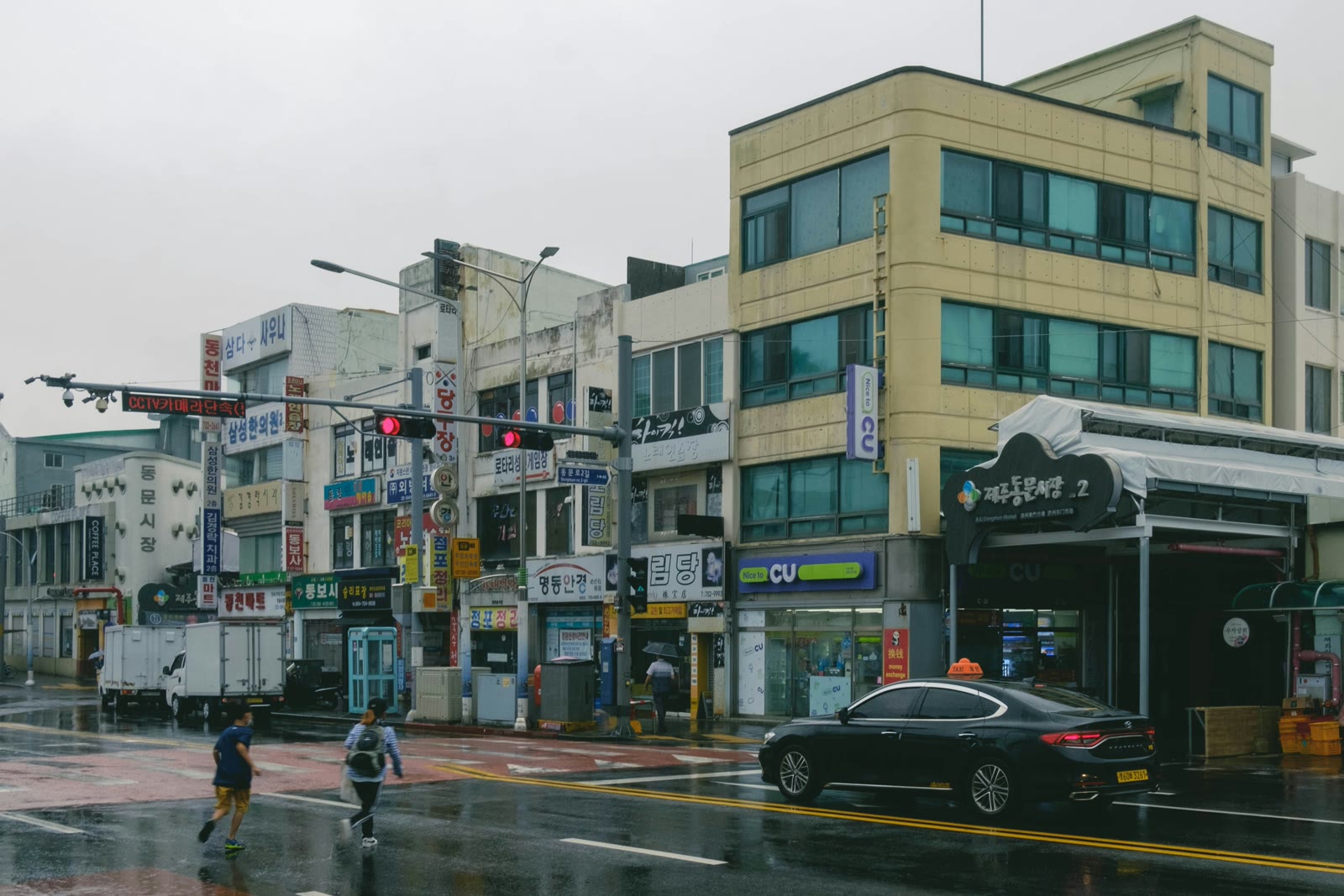 People crossing a street in the rain in Jeju City, South Korea