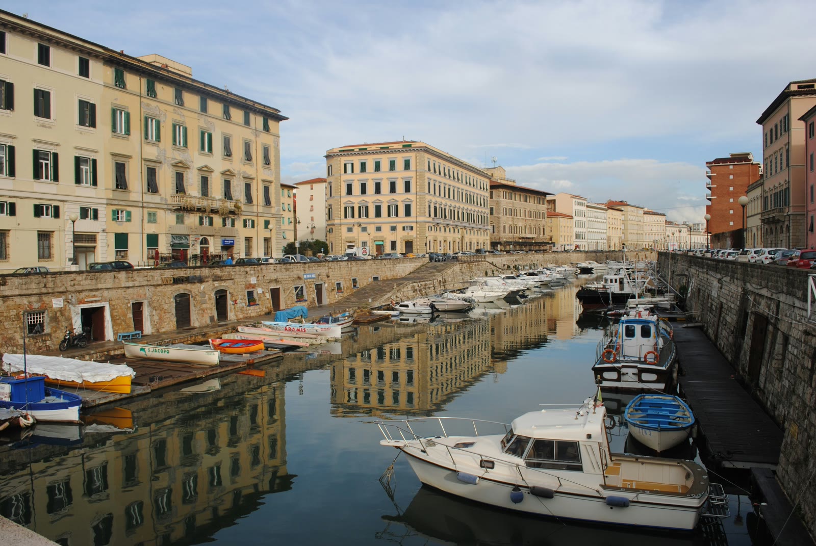 White and blue boat in the water near a brown building in the Venice district, Livorno, Tuscany, Italy