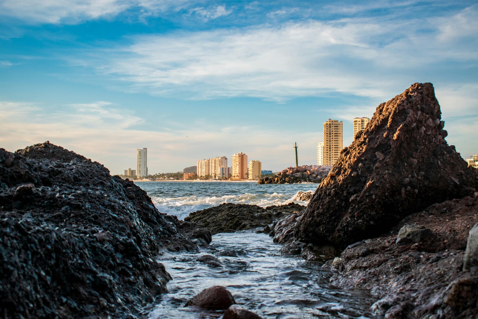 Rocky coast with waves near city buildings in Mazatlan, Sinaloa, Mexico