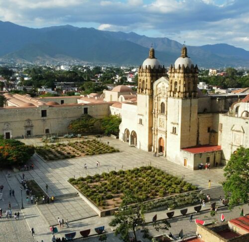 Grand building with dome and courtyard with people walking in Oaxaca City, Mexico