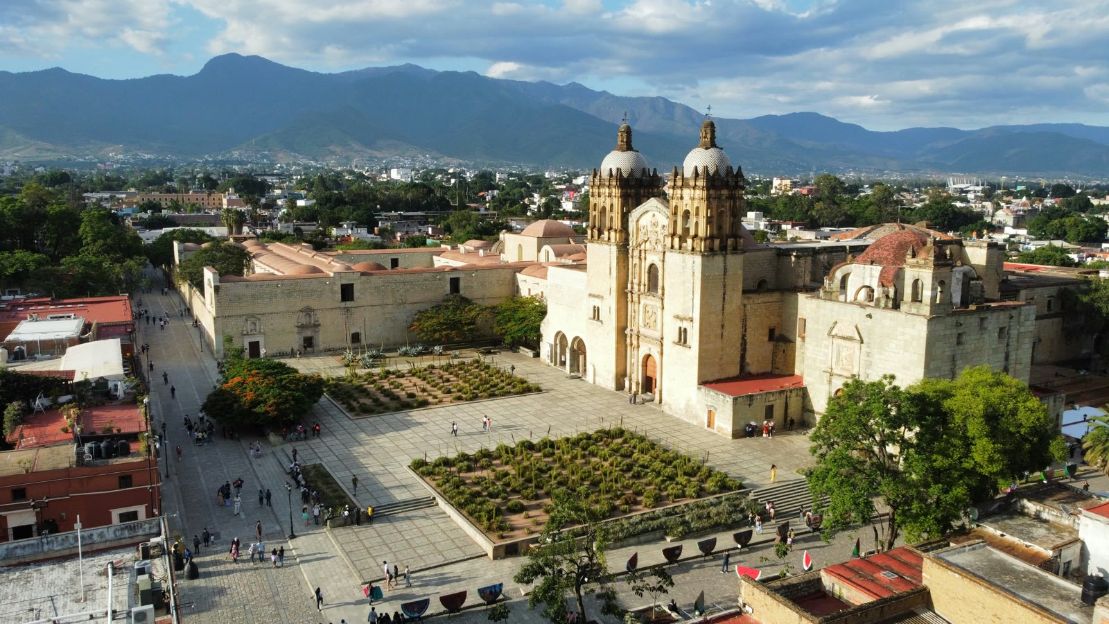 Grand building with dome and courtyard with people walking in Oaxaca City, Mexico