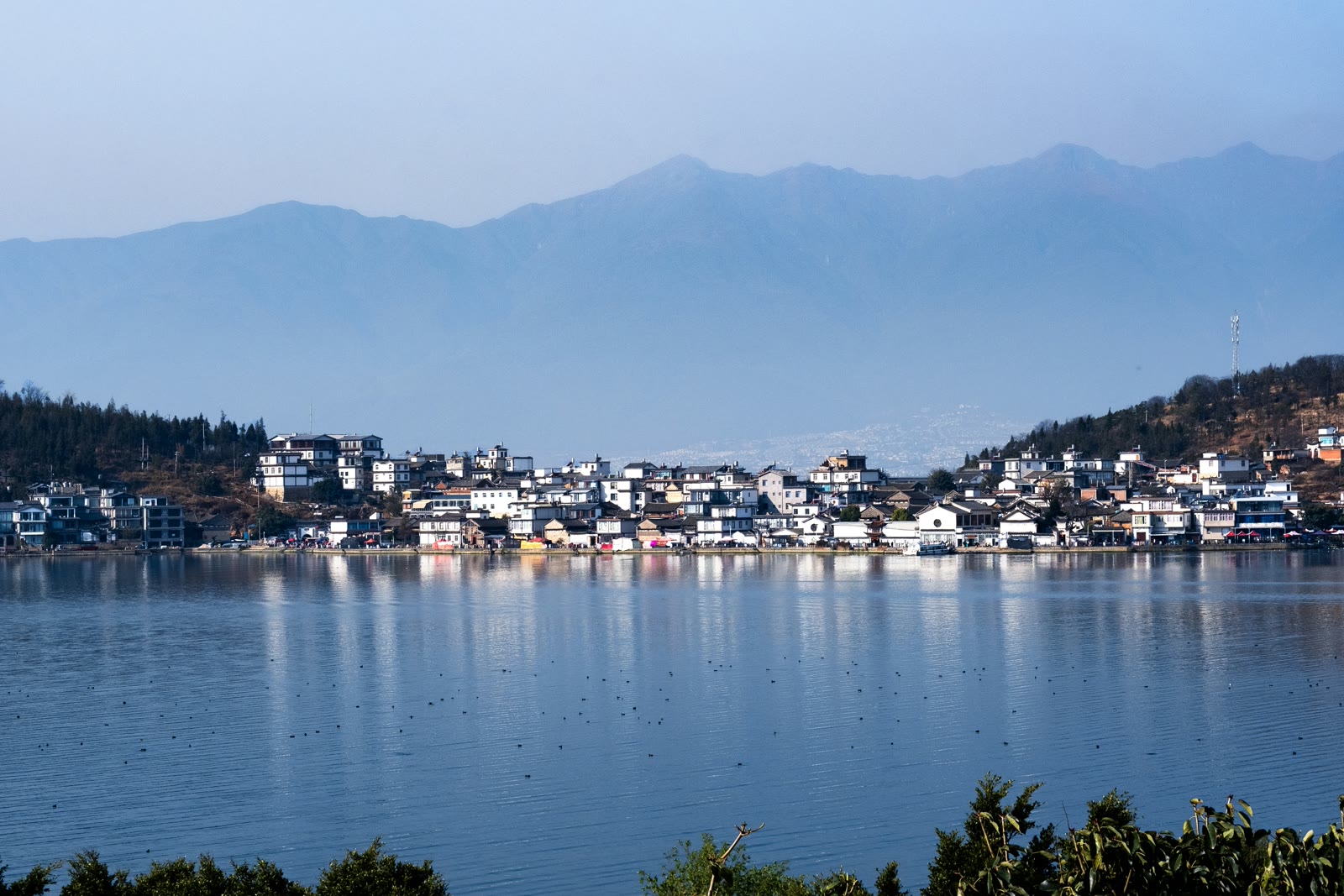 City on a lake with mountains in the background in Dali, Yunnan, China