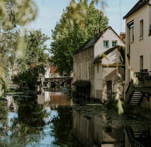 River through a city with tall buildings in Chartres, France