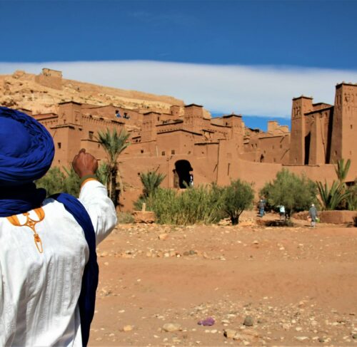 Person in a white shirt and blue hat standing on sand in Ouarzazate, Morocco