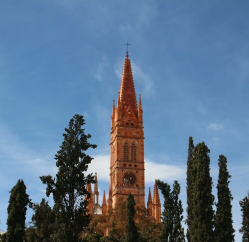 Brown building near green trees under blue sky in Zacatecas, Mexico