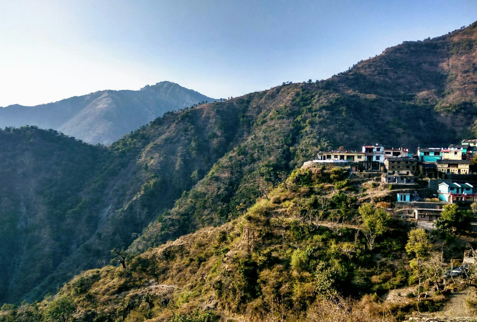 Green and brown mountain under blue sky in Dehradun, Uttarakhand, India