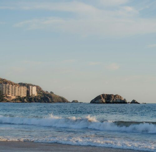 Palm-lined beach with a resort in the distance in Ixtapa, Guerrero, Mexico