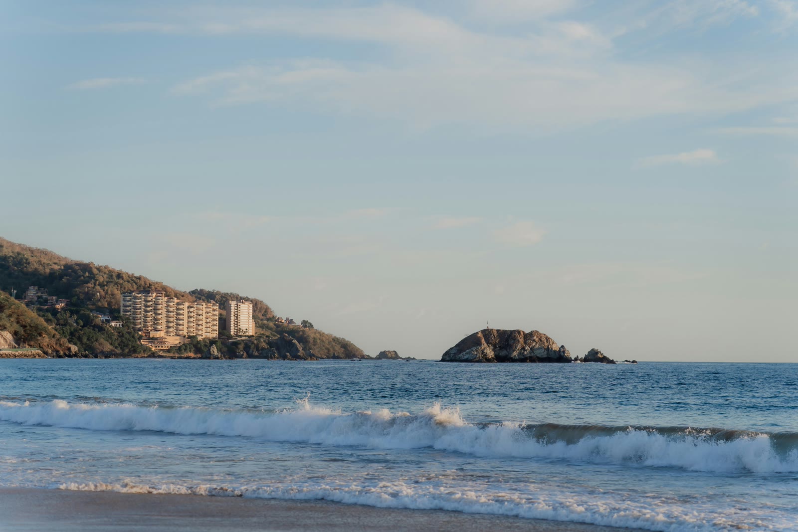 Palm-lined beach with a resort in the distance in Ixtapa, Guerrero, Mexico